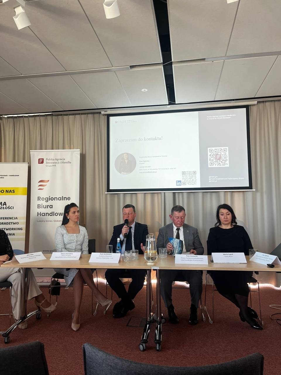 Expert panel at “Kazakhstan – New Opportunities for Polish Business”, with panelists seated in front of presentation slides.