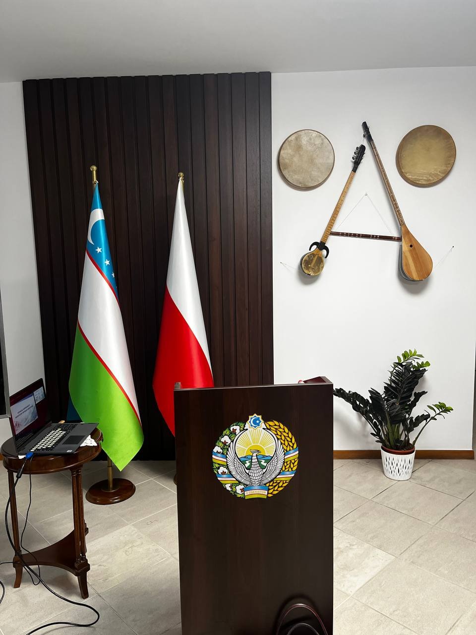 Mównica z godłem Uzbekistanu w ambasadzie w Warszawie, w tle tradycyjne uzbeckie instrumenty muzyczne.
